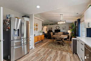 Kitchen with light countertops, hanging light fixtures, appliances with stainless steel finishes, open floor plan, and white cabinets