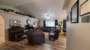 Living room with baseboards, arched walkways, lofted ceiling, ceiling fan, and wood finished floors