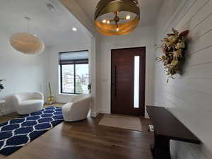 The foyer with a beautiful gold chandelier, recessed lighting, dark wood finished floors, and baseboards