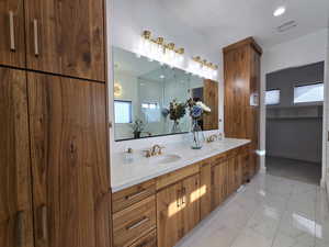 The bathroom features a marble finish floor, visible vents, a double sink, and a double vanity