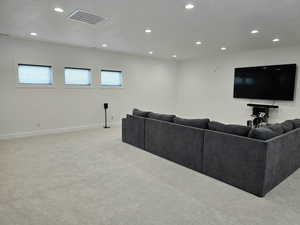 Living/Media room with a textured ceiling, light-colored carpet, recessed lighting, visible vents, and baseboards