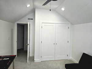 Bedroom with visible vents, baseboards, light-colored carpet, lofted ceiling, and ceiling fan