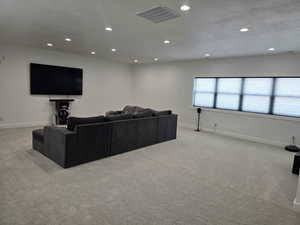 Living/Media room with a textured ceiling, light-colored carpet, recessed lighting, visible vents, and baseboards