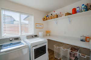 Laundry room with laundry area, washing machine and clothes dryer, and wood finished floors