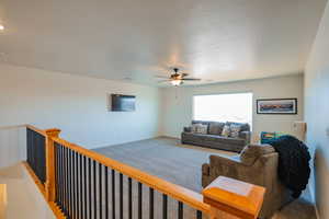 Carpeted living area featuring visible vents, baseboards, and ceiling fan