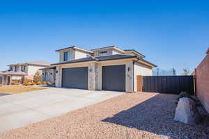 View of front facade with a garage, concrete driveway, fence, and stucco siding