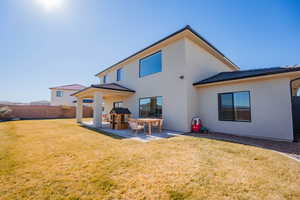 Rear view of house with a patio area, a yard, fence, and stucco siding