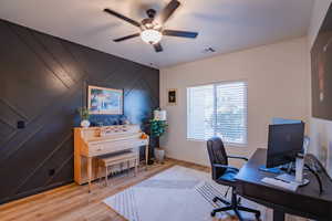 Office area with light wood finished floors, ceiling fan, visible vents, and baseboards