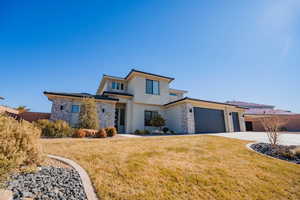 View of front facade featuring driveway, an attached garage, fence, a front lawn, and stucco siding