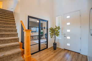 Entryway featuring a high ceiling, stairway, wood finished floors, and baseboards