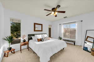 Bedroom with a ceiling fan, visible vents, light carpet, and baseboards