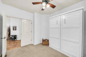 Bedroom featuring baseboards, ceiling fan, a closet, and light colored carpet