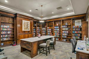 Office space with light carpet, visible vents, a raised ceiling, wall of books, and recessed lighting