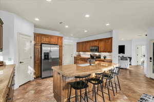 Kitchen featuring light stone counters, a center island with sink, visible vents, appliances with stainless steel finishes, and a sink