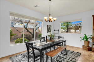 Dining area with baseboards, light tile patterned floors, visible vents, and a notable chandelier