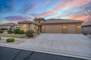 Mediterranean / spanish-style house with driveway, an attached garage, a tiled roof, and stucco siding