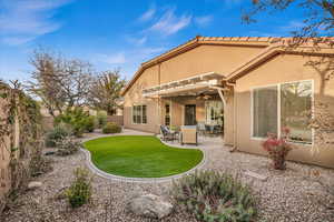 Rear view of property with stucco siding, a lawn, a ceiling fan, a fenced backyard, and a tiled roof