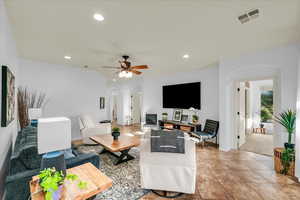 Living room featuring arched walkways, a ceiling fan, visible vents, and recessed lighting