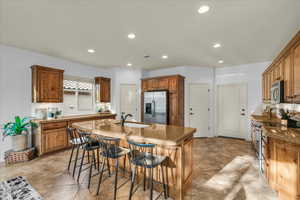 Kitchen featuring appliances with stainless steel finishes, brown cabinetry, a sink, and a kitchen island with sink