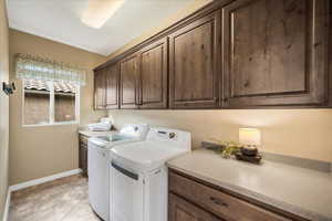 Laundry room featuring cabinet space, washer and clothes dryer, and baseboards