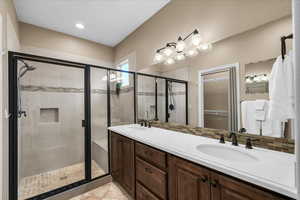 Full bath featuring a sink, a spacious closet, a shower stall, and double vanity