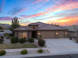 Mediterranean / spanish house featuring a tile roof, driveway, an attached garage, and stucco siding