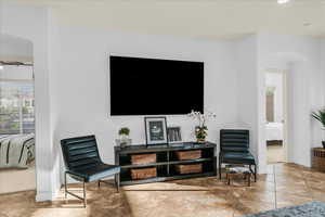 Living area with arched walkways, baseboards, and tile patterned floors