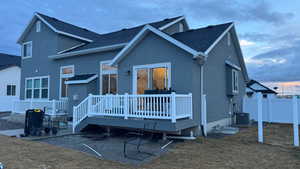 Back house at dusk featuring central AC unit and a deck