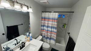 Full bathroom with shower / bath combo, vanity, a textured ceiling, and toilet