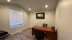 Office space with lofted ceiling and hardwood / wood-style floors