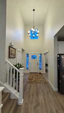 Foyer with an inviting chandelier, wood-type flooring, and a high ceiling