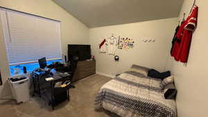 Bedroom with lofted ceiling, light carpet, and a textured ceiling