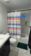 Full bathroom featuring vanity, shower / tub combo with curtain, a textured ceiling, and toilet