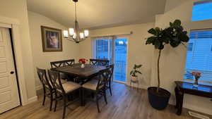 Dining area with wood-type flooring, lofted ceiling, and a chandelier