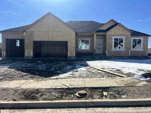 Property under construction with a garage, a shingled roof, and stucco siding