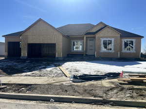 Unfinished property featuring an attached garage, roof with shingles, and stucco siding