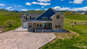 Exterior space with driveway, a shingled roof, stone siding, a mountain view, and a porch