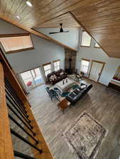 Living room with wood ceiling, high vaulted ceiling, wood finished floors, and a wood stove