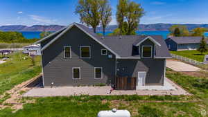 Back of property featuring a patio area, roof with shingles, fence, and a water and mountain view