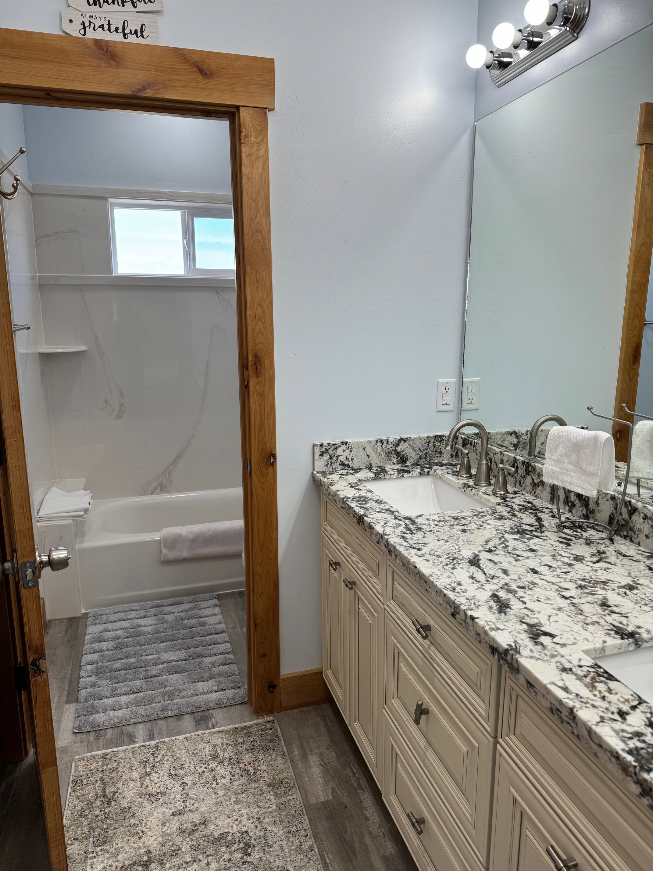 Primary Bathroom featuring double vanity, wood finished floors, tub / shower combination, and a sink