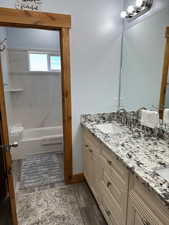 Primary Bathroom featuring double vanity, wood finished floors, tub / shower combination, and a sink