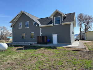 Back of house with patio, roof with shingles and a lawn