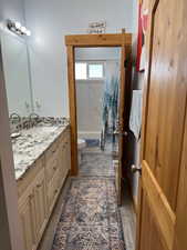 Full bathroom featuring double vanity, toilet, shower / tub combo, a sink, and wood finished floors