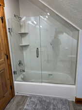 Bathroom featuring bath / shower combo with glass door and wood finished floors