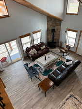 Living area with high vaulted ceiling, a wood stove, and a healthy amount of sunlight