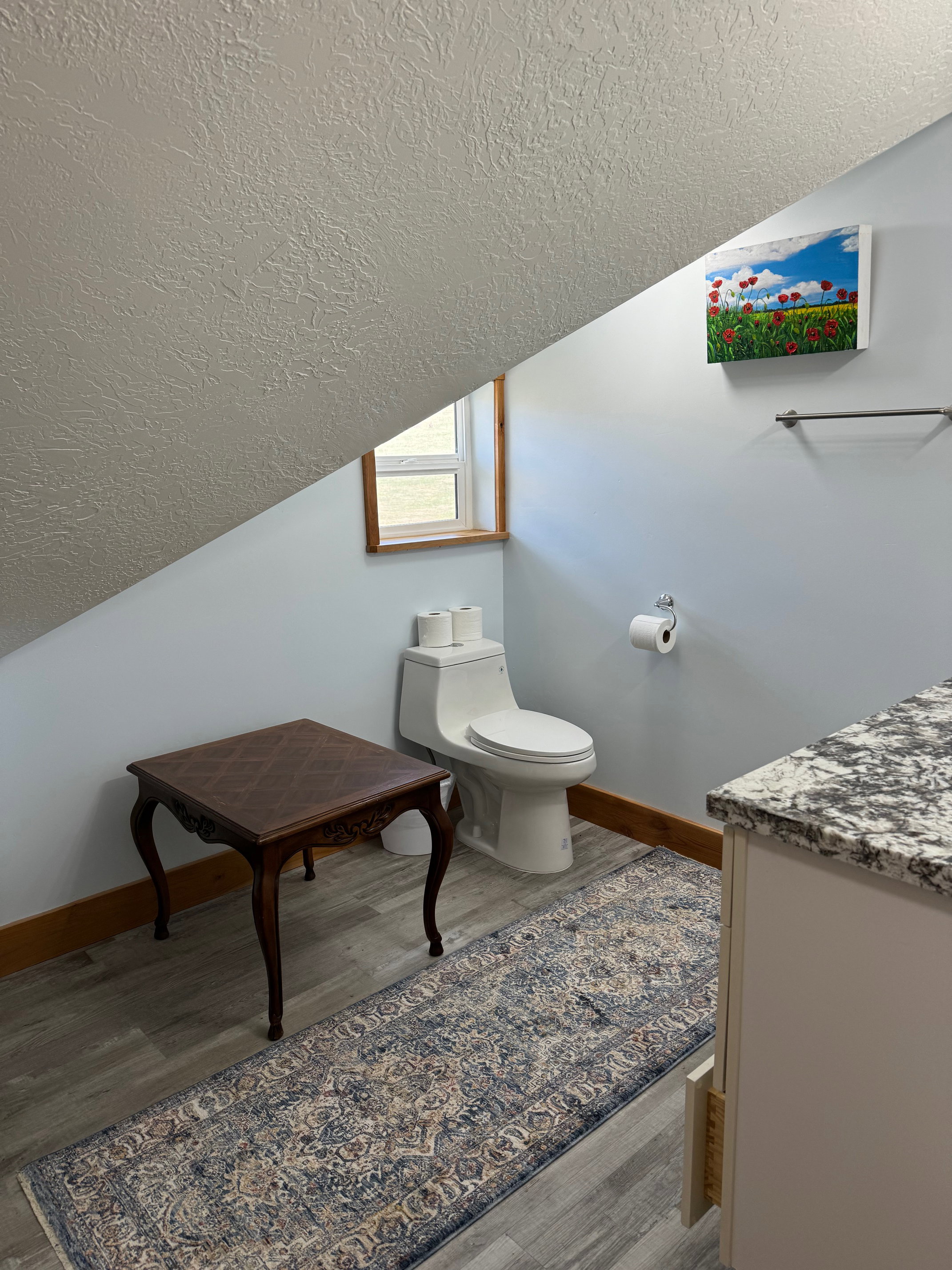 Bathroom with a textured ceiling, wood finished floors, toilet, and lofted ceiling