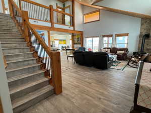 Living room with visible vents, a gas stove, wood finished floors, high vaulted ceiling, and stairs