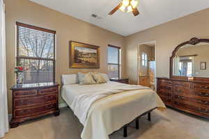 Bedroom featuring a ceiling fan, visible vents, connected bathroom, and light carpet