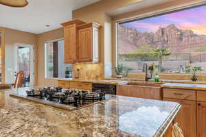 Kitchen with tasteful backsplash, stainless steel gas stovetop, a sink, a mountain view, and dishwashing machine