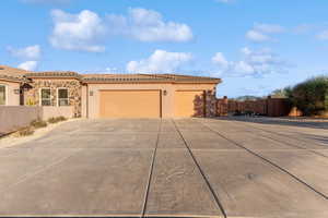 View of front of home with a tile roof, stucco siding, concrete driveway, fence, and a garage